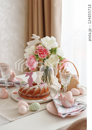 Table setting with traditional easter cakes with icing decorated with gingerbread cookies in shape of rabbits on white wooden table 124855718