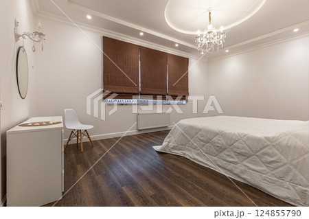 Elegant Bedroom with Chandelier and Brown Blinds 124855790