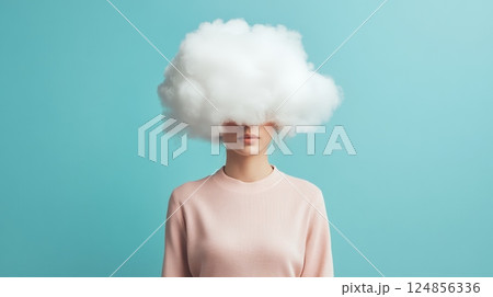 Studio portrait of young woman with a cloud obscuring her face, symbolizing thoughts, dreams, and mental health struggles against a vibrant teal background 124856336