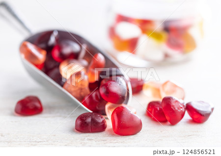 Heart shaped jelly candies in scoop on white table. 124856521