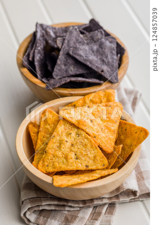 Dark and yellow nachos chips in bowl on white table. Dark and yellow nachos chips in bowl on white table. 124857039