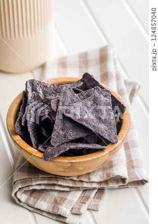 Dark nachos chips in bowl on white table. 124857040