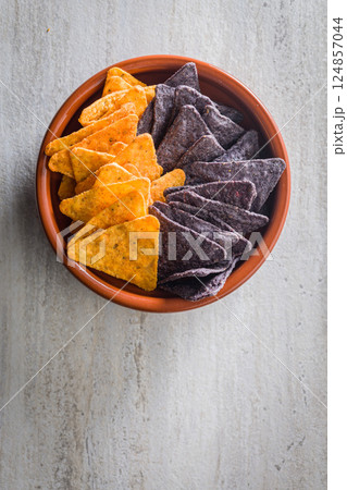 Dark and yellow nachos chips in bowl on kitchen table. Top view. 124857044