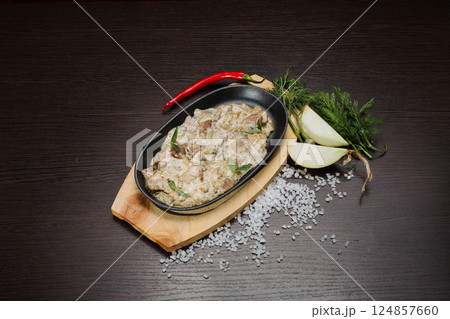 Meat in a creamy sauce with mushrooms and cheese 124857660