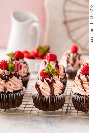 Raspberry chocolate cupcakes with raspberry buttercream frosting a drizzle of chocolate glaze 124859278