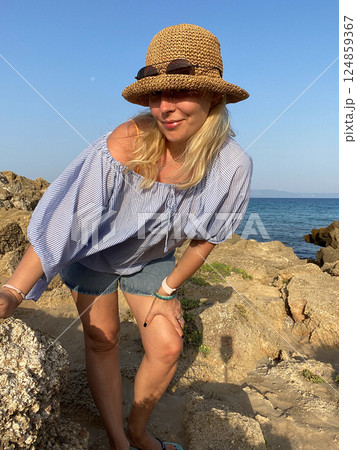 Woman relaxing on rocks by the sea 124859367
