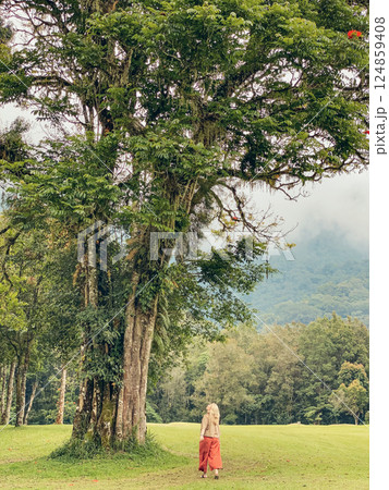 Woman walking near big tree Woman walking near big tree 124859408