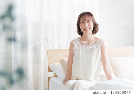 朝ベッドから起床する中高年女性 124860077