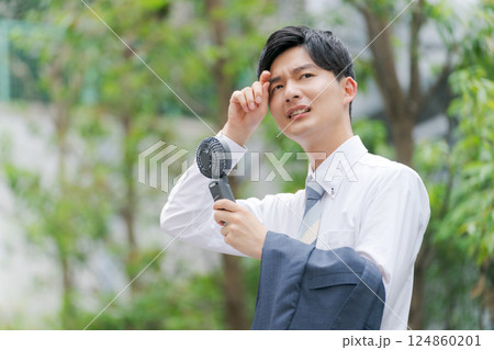 ハンディファンを持つ夏のビジネスマン 124860201