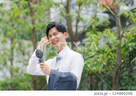 ハンディファンを持つ夏のビジネスマン 124860206
