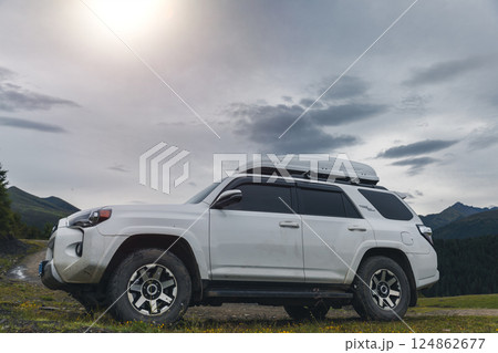Offroad car on flowering grassland mountain under sky 124862677
