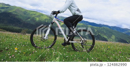 Riding mountain bike on grassland mountain top Riding mountain bike on grassland mountain top 124862990