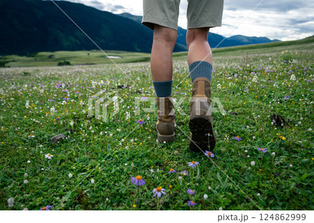 Hiker legs walking on beautiful flowering grassland Hiker legs walking on beautiful flowering grassland 124862999