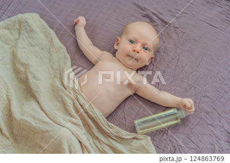A mother gently massages her 1-month-old baby with baby oil after a bath. This tender moment highlights the bond between parent and child, promoting relaxation, baby care, and the importance of skin 124863769