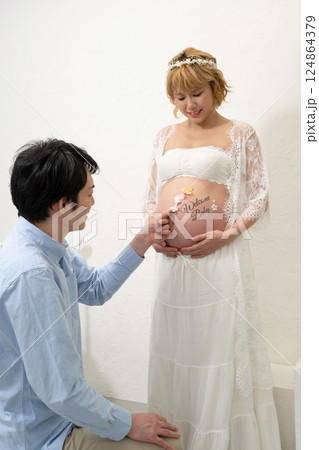 妊娠妻のお腹ににシールを貼る夫 妊娠妻のお腹ににシールを貼る夫 124864379