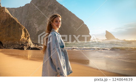 Smiling woman in denim shirt standing on beach Smiling woman in denim shirt standing on beach 124864639