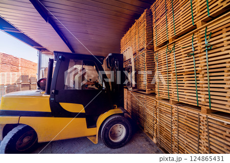 Forklift loader load lumber into a dry kiln. Wood drying in containers. Forklift loader load lumber into a dry kiln. Wood drying in containers. 124865431