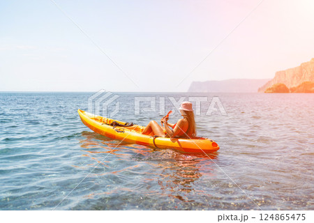 Kayak sea woman. Happy attractive woman with long hair in red swimsuit, swimming on kayak. Summer holiday vacation and travel concept. 124865475