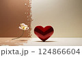 A bright red heart is resting on a wooden table beside a flower 124866604
