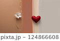 A red heart hangs on a wall next to a lovely white flower 124866608