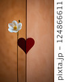 A pristine white flower is elegantly standing next to a bright red heart 124866611