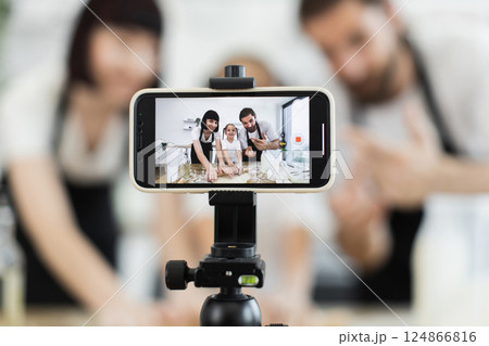 Caucasian family of two adults and one child filming cooking vlog in bright kitchen. 124866816