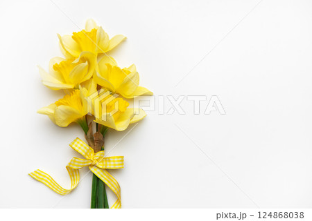 Yellow daffodils with ribbon bow lying on white background Yellow daffodils with ribbon bow lying on white background 124868038