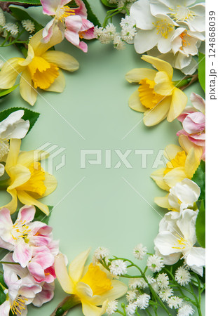 Daffodils and apple blossoms creating a floral frame on green background Daffodils and apple blossoms creating a floral frame on green background 124868039