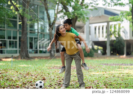 Active Fun and Playful Bonding. A girl carries a boy on her back while a soccer ball rests nearby. 124868099