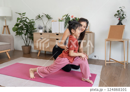 Health and Movement. A mother nurturing healthy habits in her daughter through stretching exercises at home. 124868101