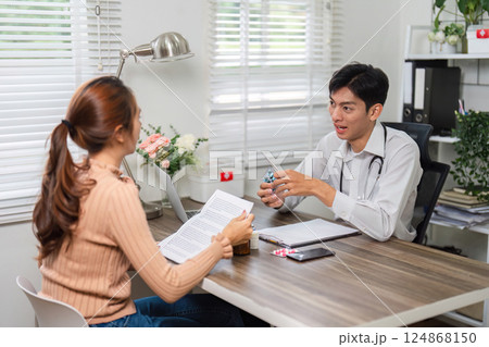 Patient Care and Medication Review. A doctor discussing health plans with a female patient in a clinical setting. 124868150
