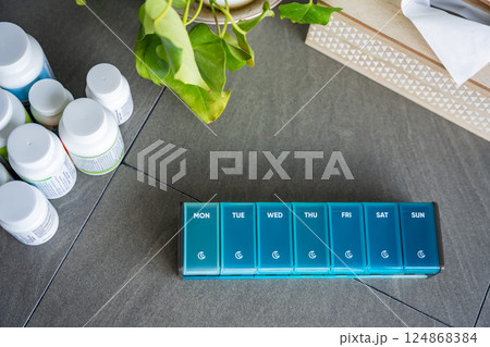 Weekly pill organizer with labeled compartments for daily medication doses. Concept of health management and medication planning 124868384