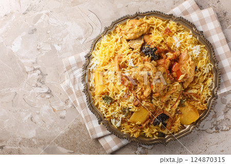 Delicious chicken pilaf with basmati, potatoes, tomatoes, onions and prunes close-up in a plate. Horizontal top view Delicious chicken pilaf with basmati, potatoes, tomatoes, onions and prunes close-up in a plate. Horizontal top view 124870315