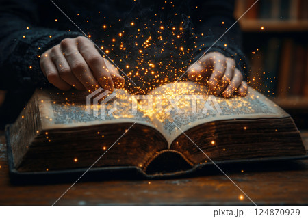 開かれた古書から光が舞い上がる手元 開かれた古書から光が舞い上がる手元 124870929