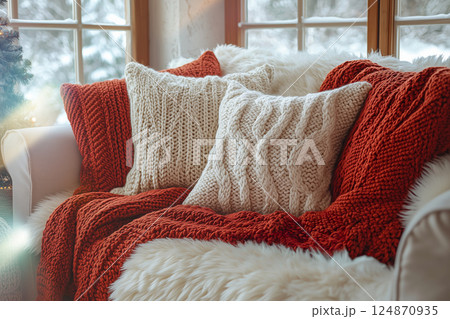 雪景色を背景に並ぶ白と赤のニットクッションとブランケット 124870935