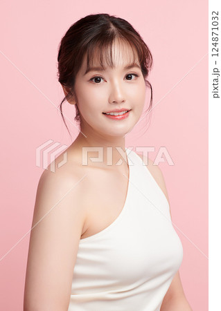 A beautiful young Asian woman with clean, fresh skin against a pink background. Skincare, facial treatment, cosmetology, beauty, and spa. An elegant portrait of an Asian woman. A beautiful young Asian woman with clean, fresh skin against a pink background. Skincare, facial treatment, cosmetology, beauty, and spa. An elegant portrait of an Asian woman. 124871032