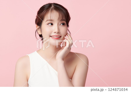 A beautiful young Asian woman with clean, fresh skin against a pink background. Skincare, facial treatment, cosmetology, beauty, and spa. An elegant portrait of an Asian woman. A beautiful young Asian woman with clean, fresh skin against a pink background. Skincare, facial treatment, cosmetology, beauty, and spa. An elegant portrait of an Asian woman. 124871034