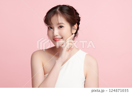 A beautiful young Asian woman with clean, fresh skin against a pink background. Skincare, facial treatment, cosmetology, beauty, and spa. An elegant portrait of an Asian woman. 124871035