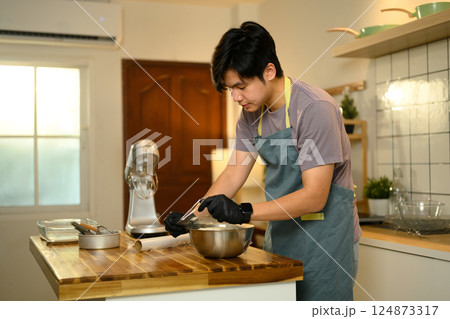 Man covers a bowl of cream mixture with plastic wrap, ready for the butter making process 124873317