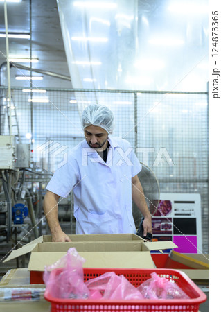 Factory worker sorting products in packaging area of a modern food processing plant Factory worker sorting products in packaging area of a modern food processing plant 124873366