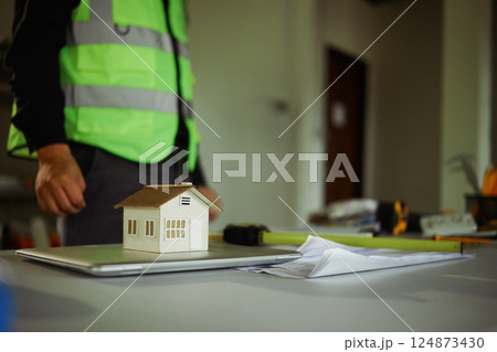 House model on desk surrounded by blueprints and measuring tools. Concept of real estate development 124873430