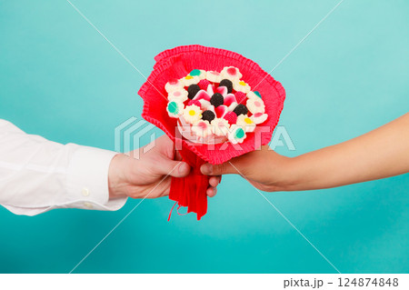 Closeup of man giving woman candy bunch flowers. Closeup of man giving woman candy bunch flowers. 124874848