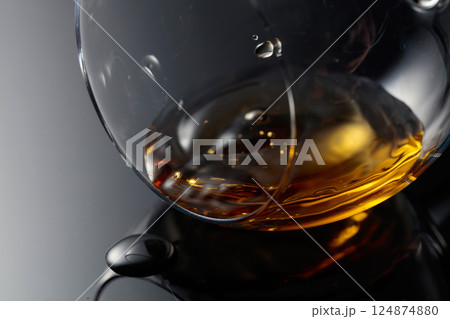Glass of brandy on a black reflective background. 124874880