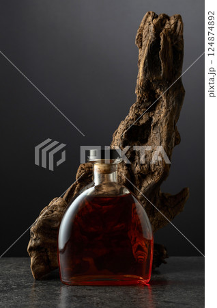 Bottle of brandy and old snag on a black background. 124874892