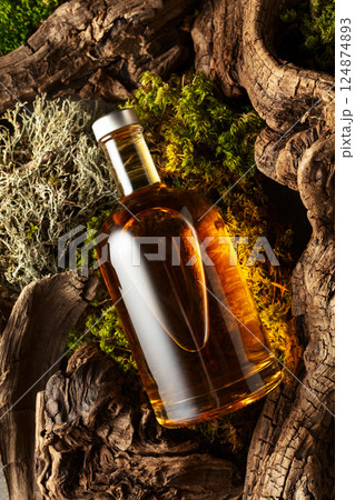 Bottle of strong alcoholic drink, old snags, and moss. 124874893