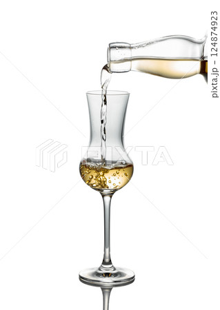 Gold liquor pouring into a glass on a white background. Gold liquor pouring into a glass on a white background. 124874923