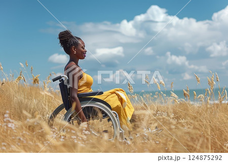 Disabled person on the beach in a wheelchair. The beach provides a joyful escape for a disabled person, who enjoys the sun and surf from their wheelchair. Disabled person on the beach in a wheelchair. The beach provides a joyful escape for a disabled person, who enjoys the sun and surf from their wheelchair. 124875292
