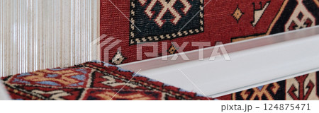 Manufacturing process, weaving of a traditional wool oriental red carpet with an intricate floral pattern, decorative elements. banner 124875471