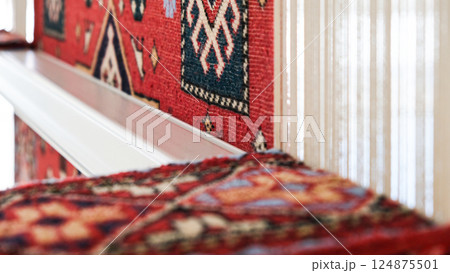 Manufacturing process, weaving of a traditional wool oriental red carpet with an intricate floral pattern, decorative elements 124875501