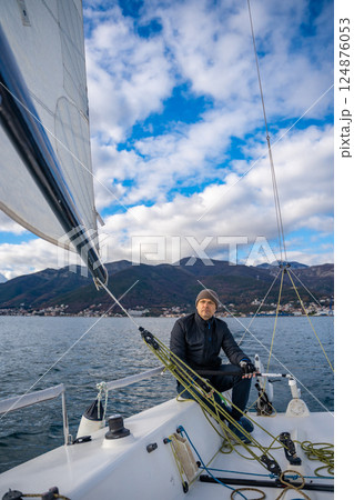 Man sailing a sports yacht in the Kotor Bay, Montenegro, showcasing adventure, freedom, and nautical sport. Man sailing a sports yacht in the Kotor Bay, Montenegro, showcasing adventure, freedom, and nautical sport. 124876053